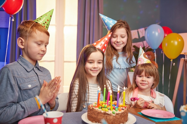 Bambini felici in cappellini per festeggiare un compleanno