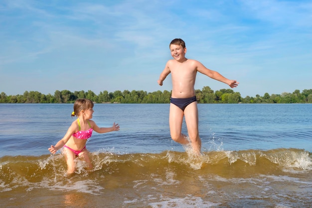 Счастливые дети играют и прыгают в воду в солнечный день счастливое детство