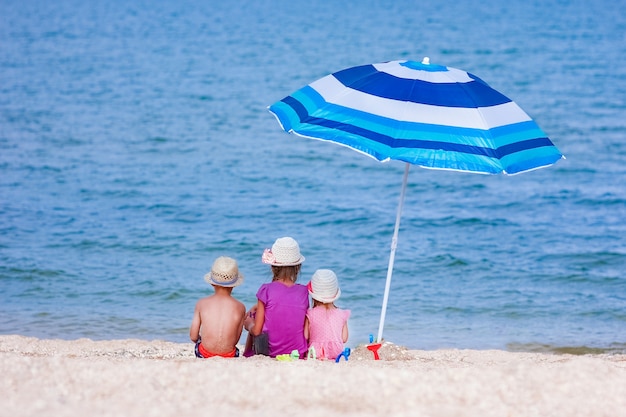 A bambini felici che giocano in riva al mare con l'ombrello