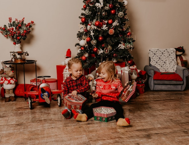 Happy children playing celebrating New Year and Christmas at decorated Christmas tree and garlands