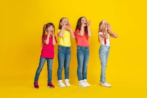 Happy children playing and having fun together on yellow  wall