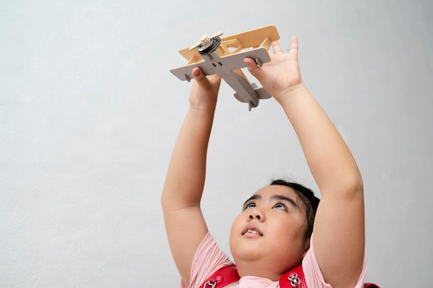 Happy children playing toy airplane on gray wall background