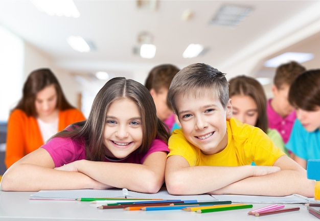 Happy children sitting by the table during lesson