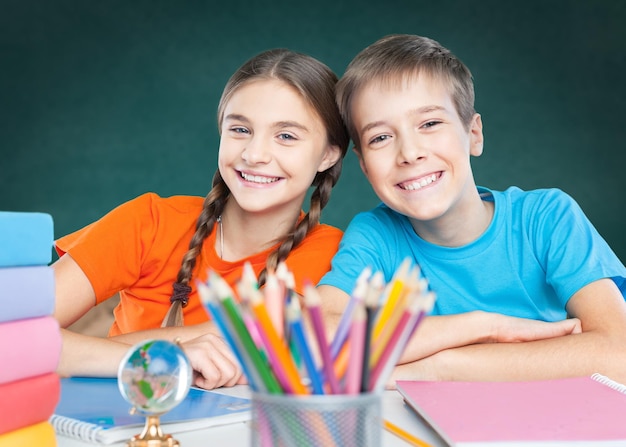 Happy children sitting by the table during lesson