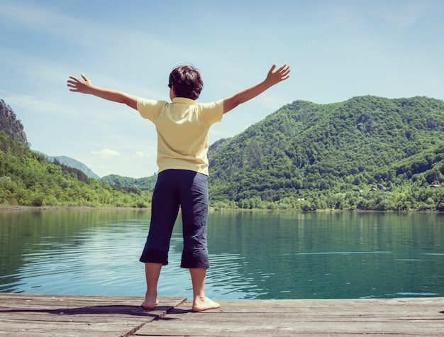 Bambini felici sulle vacanze estive divertendosi e tempo felice accanto al lago di montagna