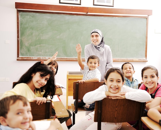 Happy children with their teacher in classroom, doing