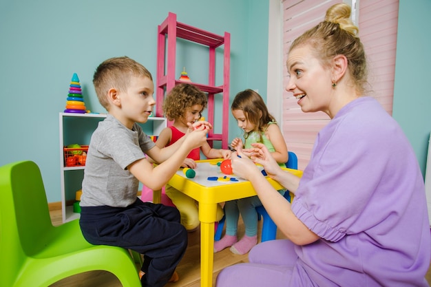 The happy children with tutors sculpt from plasticine