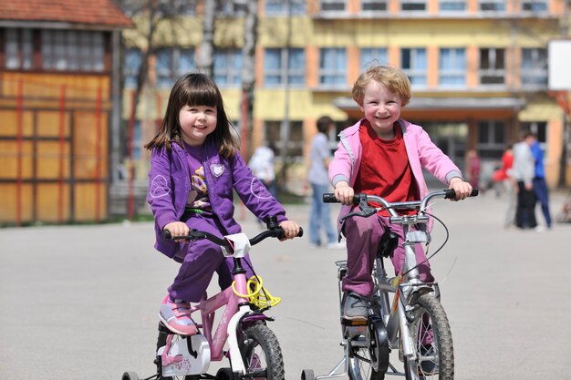 美しい晴れた春の日に屋外で自転車を運転することを学ぶ幸せな子供たちのグループ