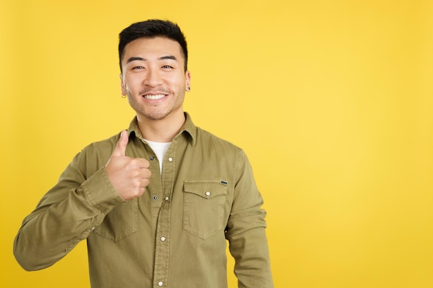 Happy chinese man gesturing agreement raising a thumb up