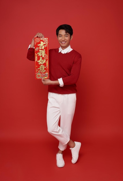 Happy Chinese new year Asian man holding greeting couplets isolated on red background