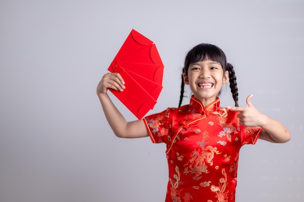 새해 복 많이 받으세요. 빨간 봉투를 들고 웃는 아시아 소녀