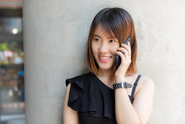 웃는 얼굴로 휴대 전화를 얘기하는 행복 한 중국 십 대 소녀