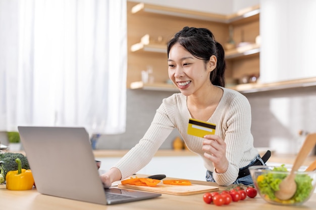 Donna cinese felice che compra cibo online utilizzando il computer