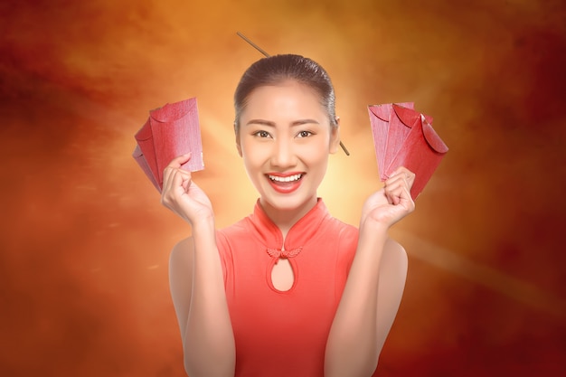 Happy chinese woman with cheongsam holding red envelopes