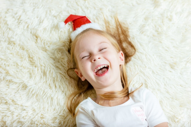 Happy christmas girl lies on a blanket and laughs.