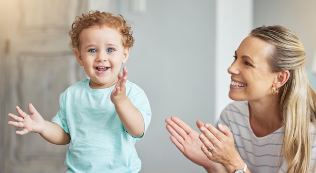 幸せな拍手の母親のサポートとリビング ルームでエネルギーを持つ子供家のラウンジでのお祝いと家族の愛のための笑顔ママと子供の発達中に喜びと拍手で赤ちゃんの肖像画