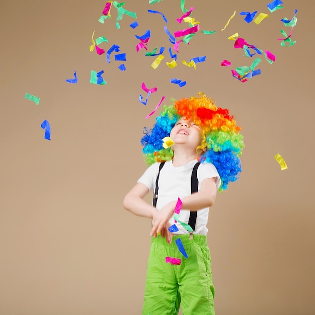 Ragazzo pagliaccio felice con grande parrucca colorata