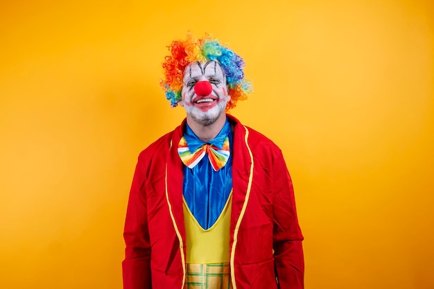 happy clown in colorful costume against vibrant yellow background