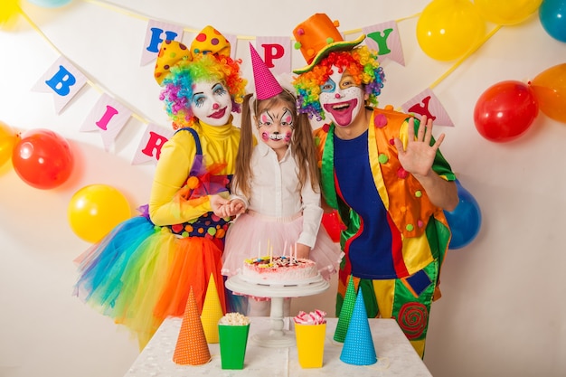 Happy clowns blow out the candles on the birthday cake at the\
holiday