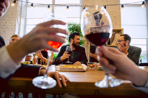 Felici colleghi che festeggiano durante la festa aziendale e l'evento aziendale. giovani caucasici in abiti da lavoro che applaudono, ridono. concetto di cultura dell'ufficio, lavoro di squadra, amicizia, vacanze, fine settimana.