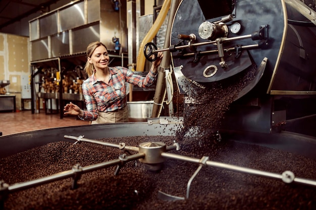 Счастливый работник кофейной фабрики обжаривает кофе на объекте