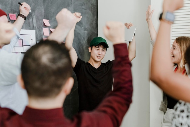 사무실에서 손을 드는 행복한 동료들