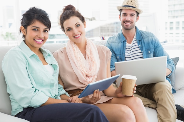 Happy colleagues sitting on couch looking at camera