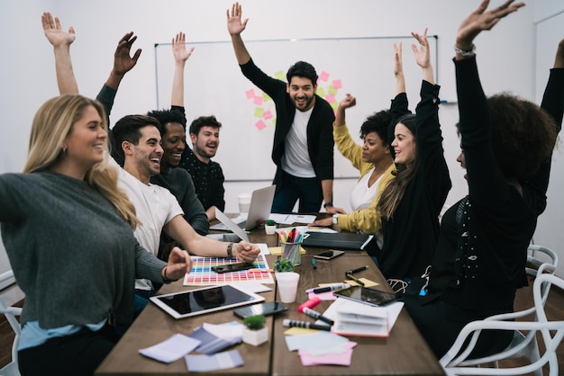 Photo happy colleagues with hand raised sitting on chairs in board room