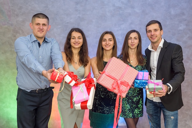 Happy colleagues with present boxes posing on abstract background