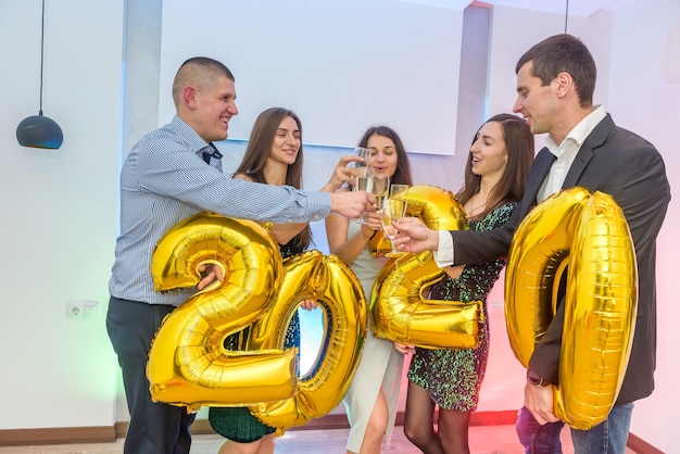 Happy company with champagne glasses celebrating new 2020 year