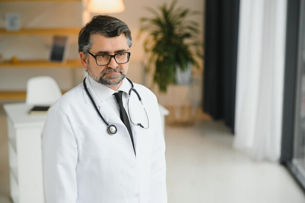 흰색 실험실 코트와 청진기 초상화를 입고 웃는 수석 성인 의사 신뢰할 수 있는 성공적인 치료사 서 행복 자신감 수염 난된 전문 의사
