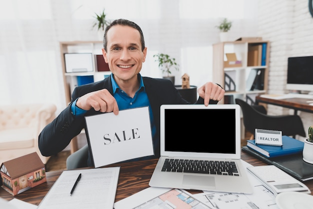 Photo happy consultant with laptop real estate office.