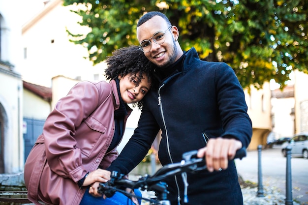 Happy and content black ethnic couple sitting on bicycle.
