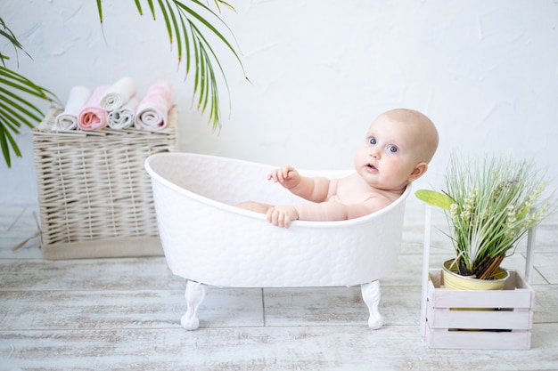 A happy, contented baby is lying in a bath, bathing, smiling, looking at the camera