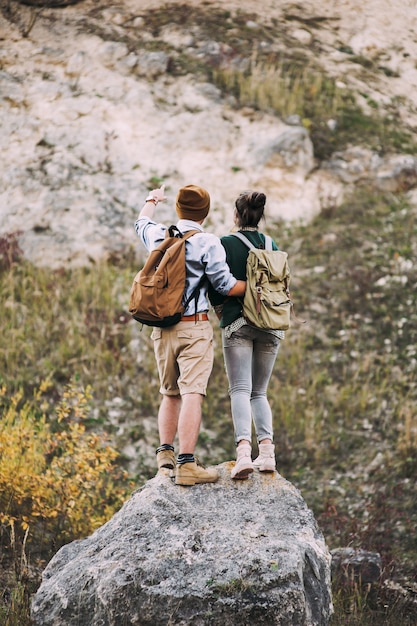 A happy couple admiring the view on the edge of a cliff in a mountain range