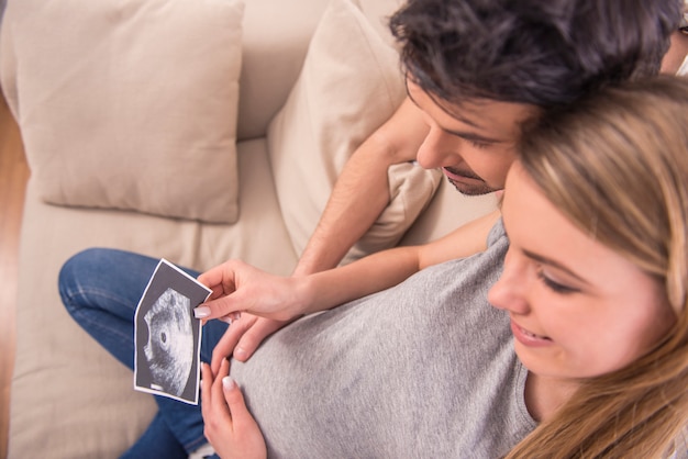 Happy couple are holding ultrasound scan of their baby.