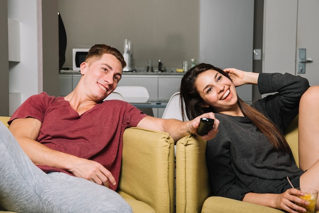 Happy couple in armchairs watching tv