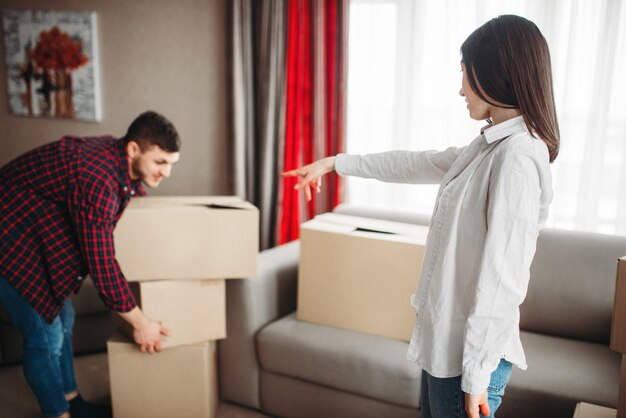 幸せなカップルが部屋に段ボール箱を配置します。