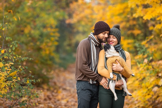 Coppia felice in autunno nel parco con carlino carino