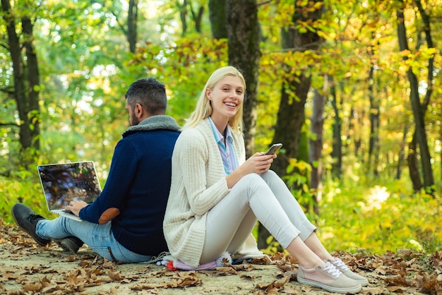 Happy couple on autumn walk business couple  man browsing internet on a notebook woman using mobile ...