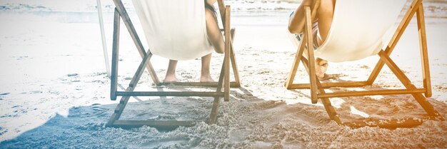 Coppia felice sulla spiaggia a bere cocktail mentre ci si rilassa sulle sedie a sdraio