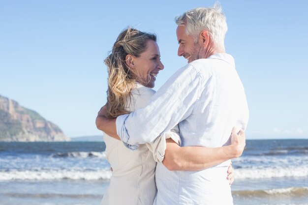 Coppie felici sulla spiaggia che sorridono a vicenda