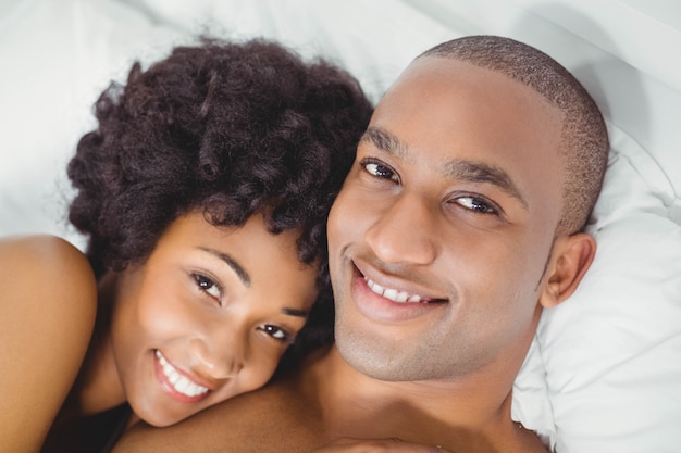 Happy couple on bed smiling at the camera at home