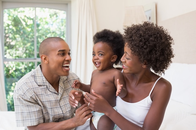 Happy couple on bed with baby daughter