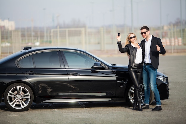 Happy couple buy new modern black car