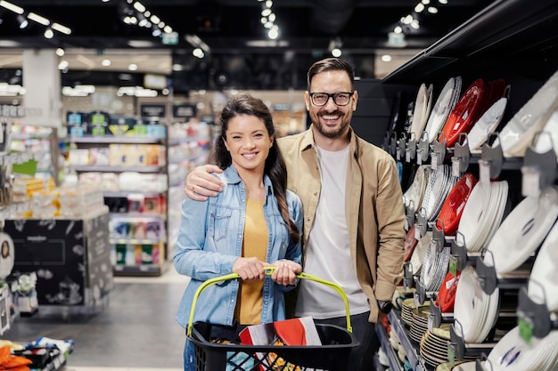 Foto coppie felici che acquistano piatti per la casa al supermercato