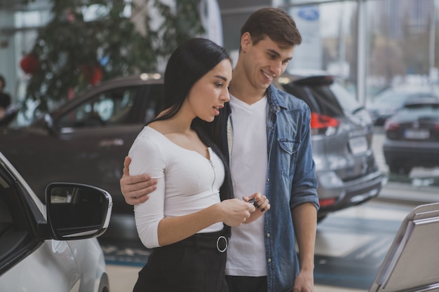 Счастливая пара покупает новую машину в салоне автосалона