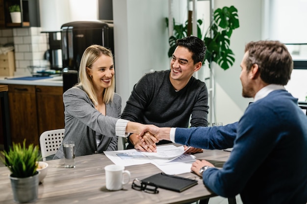 Happy couple came to an agreement with real estate agent during the meeting at home Woman is shaking hands with the agent