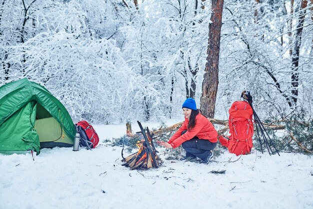 Happy couple  over a campfire in winter snowy forest