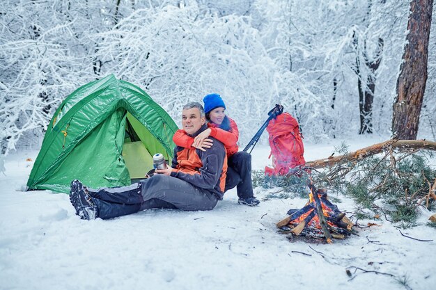 Happy couple  over a campfire in winter snowy forest